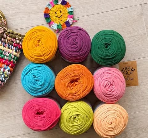 Ovillos de trapillo de distintos colores junto a una pieza de crochet.